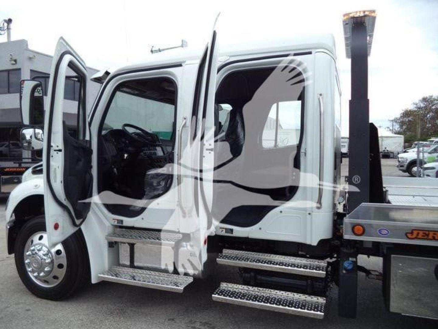 Truck cab interior with doors open showing step bars and part of rollback bed on a Freightliner M2 106.