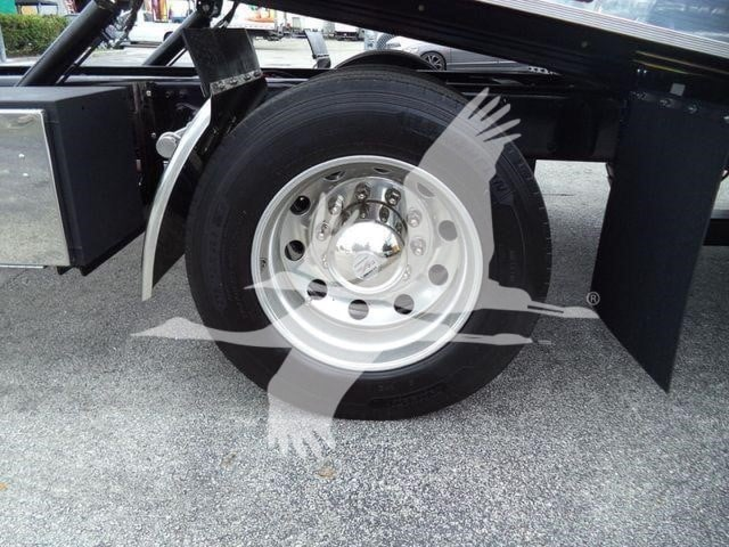 Wheel assembly and dual rear tires of a Freightliner M2 106 rollback truck showing chrome hub and black tire.
