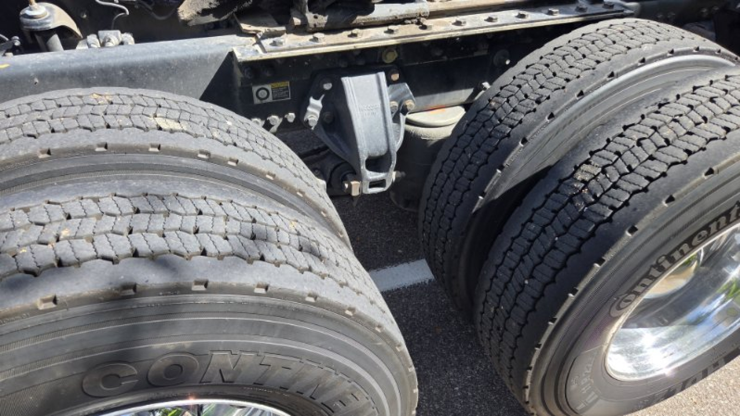 Kenworth T680 truck chassis with dual rear axles and worn tire treads; visible are parts of the frame and suspension near the wheels.