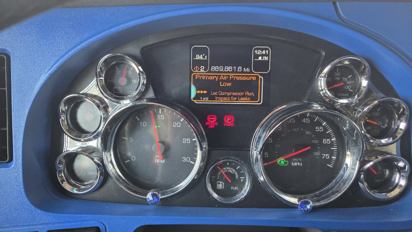 Kenworth T680 instrument cluster with multiple gauges; center digital display shows 'Primary AIR Pressure Low' warning and various gauges, including tachometer and speedometer.