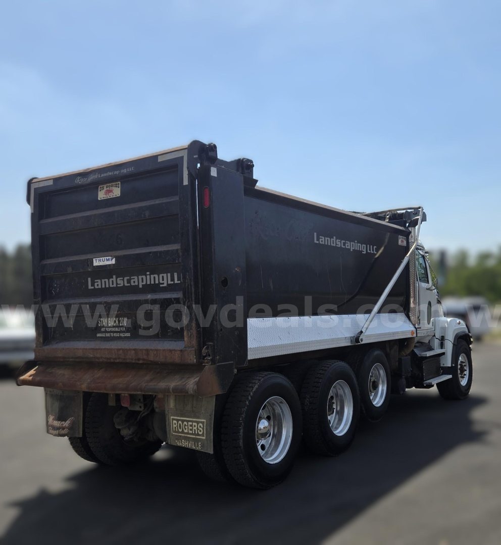 Dump truck in service showing rear and side with 'Landscaping' branding and multiple wheels.