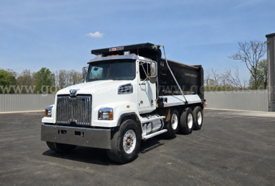 Dump truck showing Western Star 4700 with white cab and black dump bed, front grille, and dual rear axles.