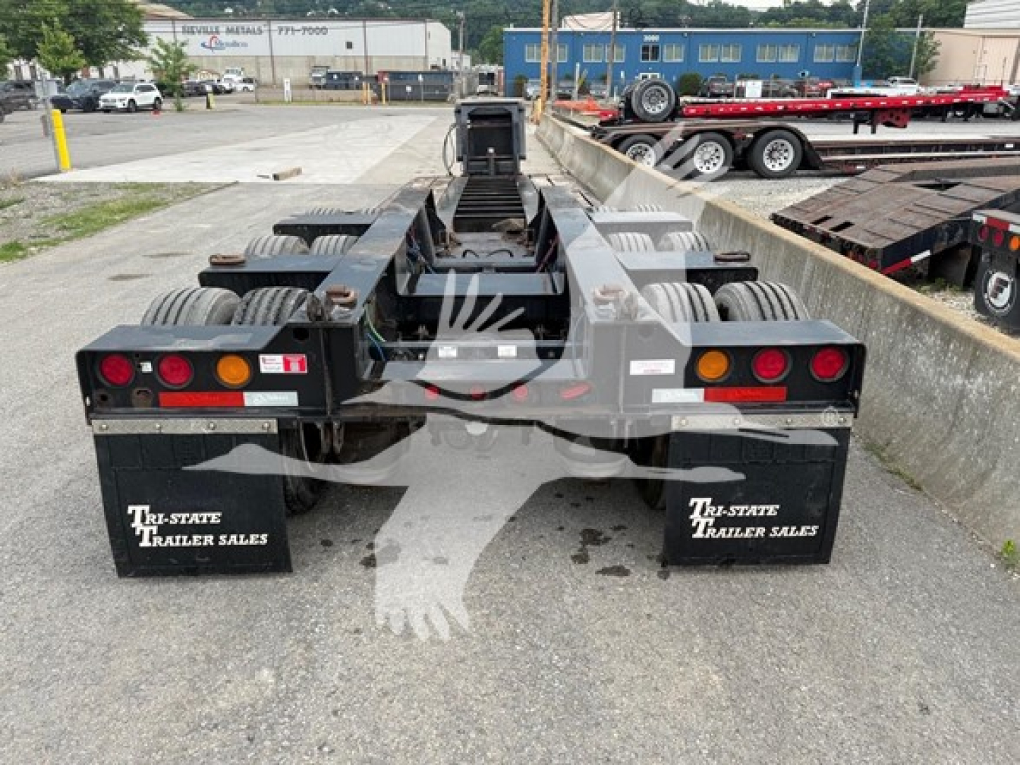 Talbert 55CC lowboy trailer rear view showing dual axle assemblies and taillights with mud flaps reading 'TRADE STATE TRIALER SALES'