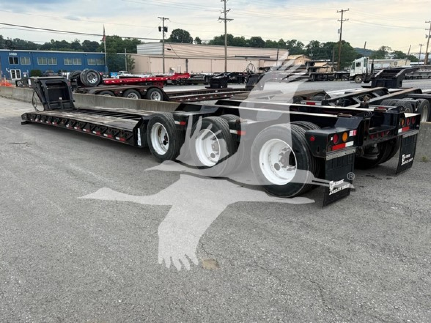 Lowboy trailer showing multiple axles and frame rails from a rear three-quarter view.