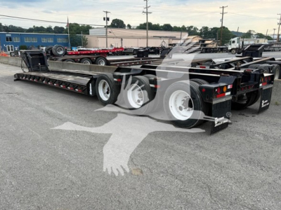 Lowboy trailer showing multiple axles and frame rails from a rear three-quarter view.