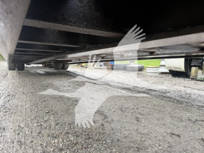 Underneath view of a 2014 Talbert 55CC lowboy trailer showing the underside frame and crossmembers with gravel ground.