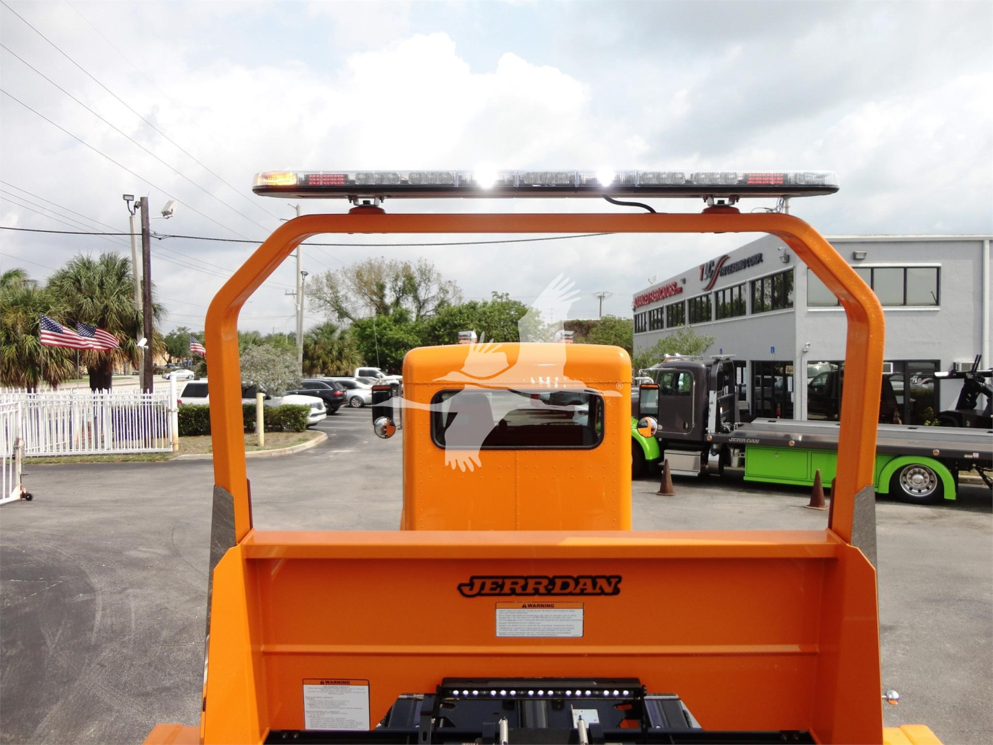 Front view of an orange JerrDan rollback truck body with a roof light bar and a Peterbilt cab in the background.