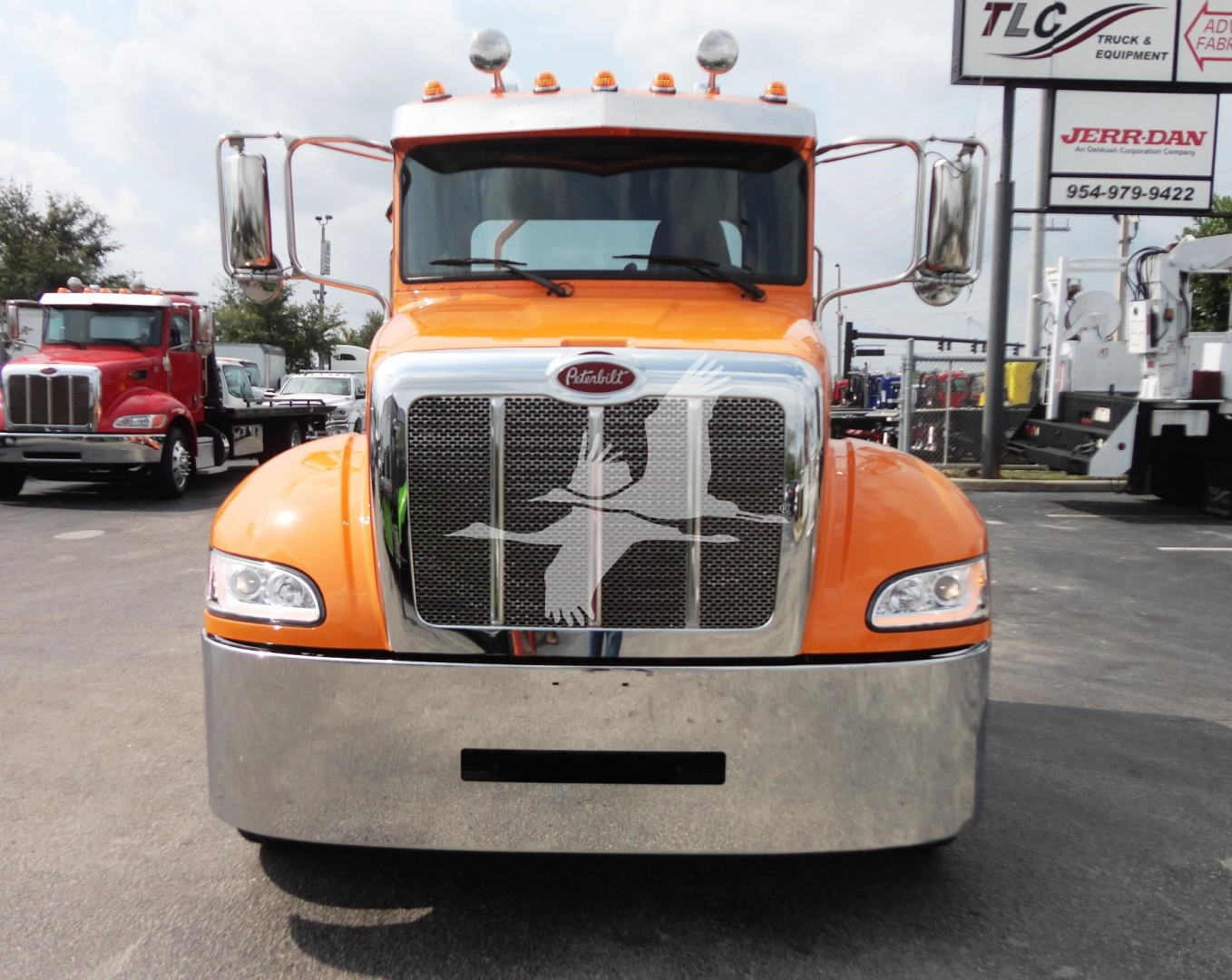 Front view of a bright orange 2022 Peterbilt 337 truck showing chrome grille and bumper.