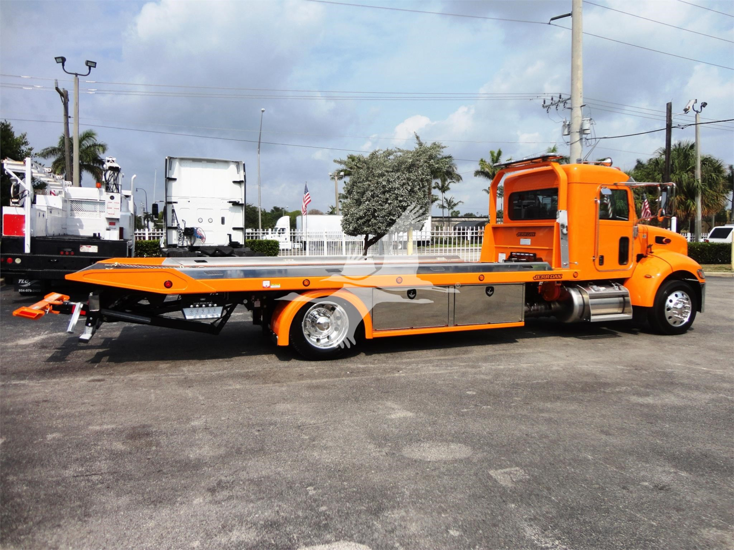 Peterbilt 337 rollback tow truck side view showing orange flatbed and cab with chrome accents