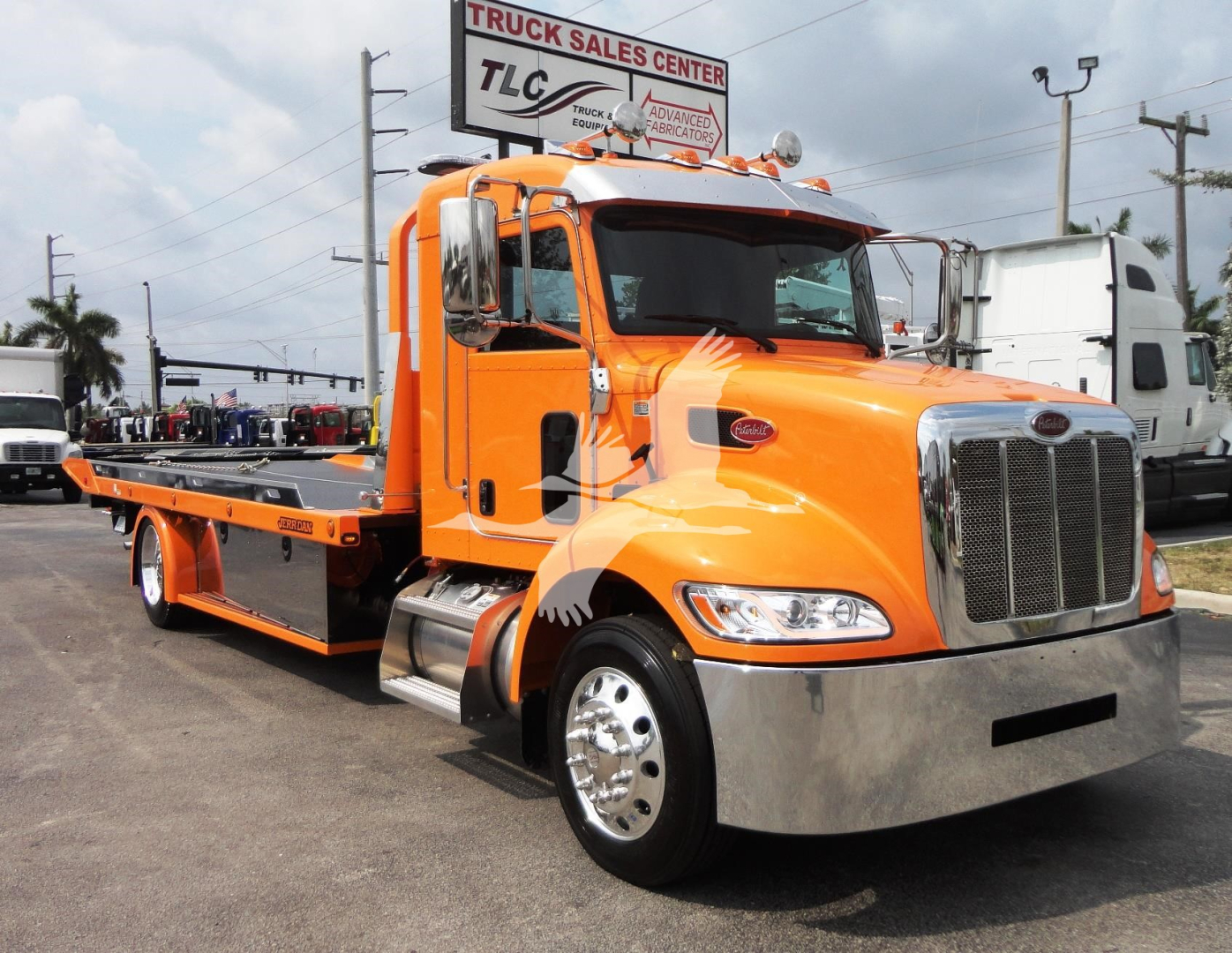 Peterbilt 337 rollback tow truck in orange with chrome front bumper and long flatbed, side mirrors, and Peterbilt badge.