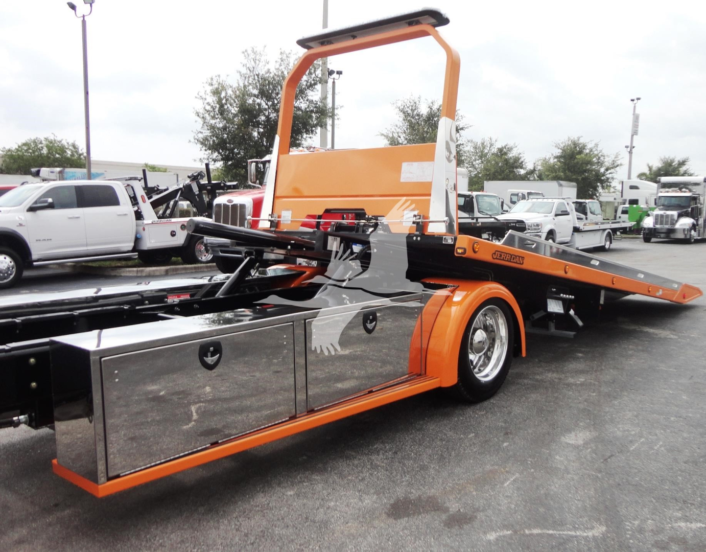 Peterbilt 337 rollback tow truck with orange and chrome service bed, side storage compartments, and a hydraulic tilt bed in view.