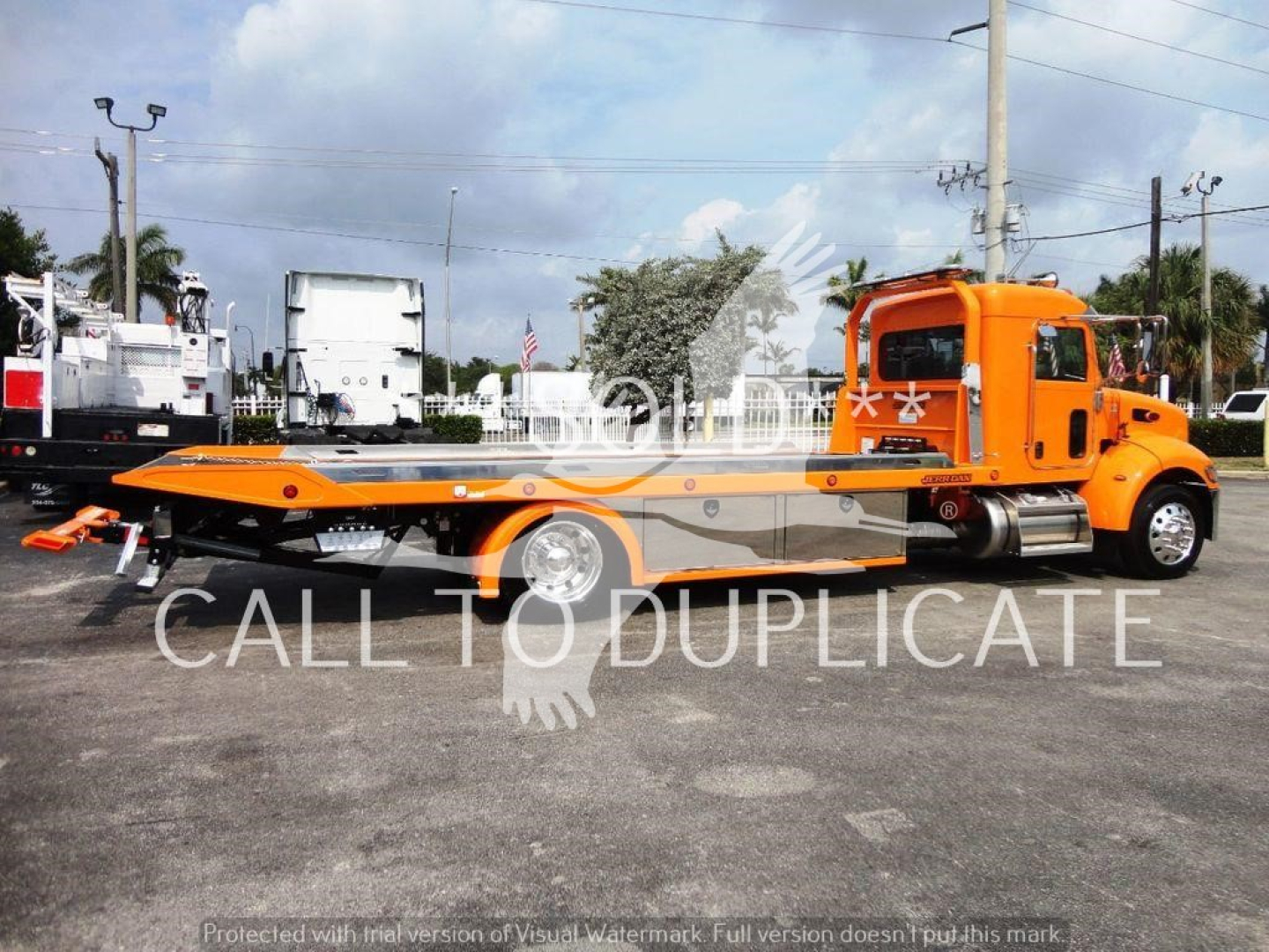 Truck showroom image of a bright orange Peterbilt 337 rollback tow truck with flatbed, side view showing cab, wheels, and equipment; watermark text across image says CALL TO DUPLICATE.