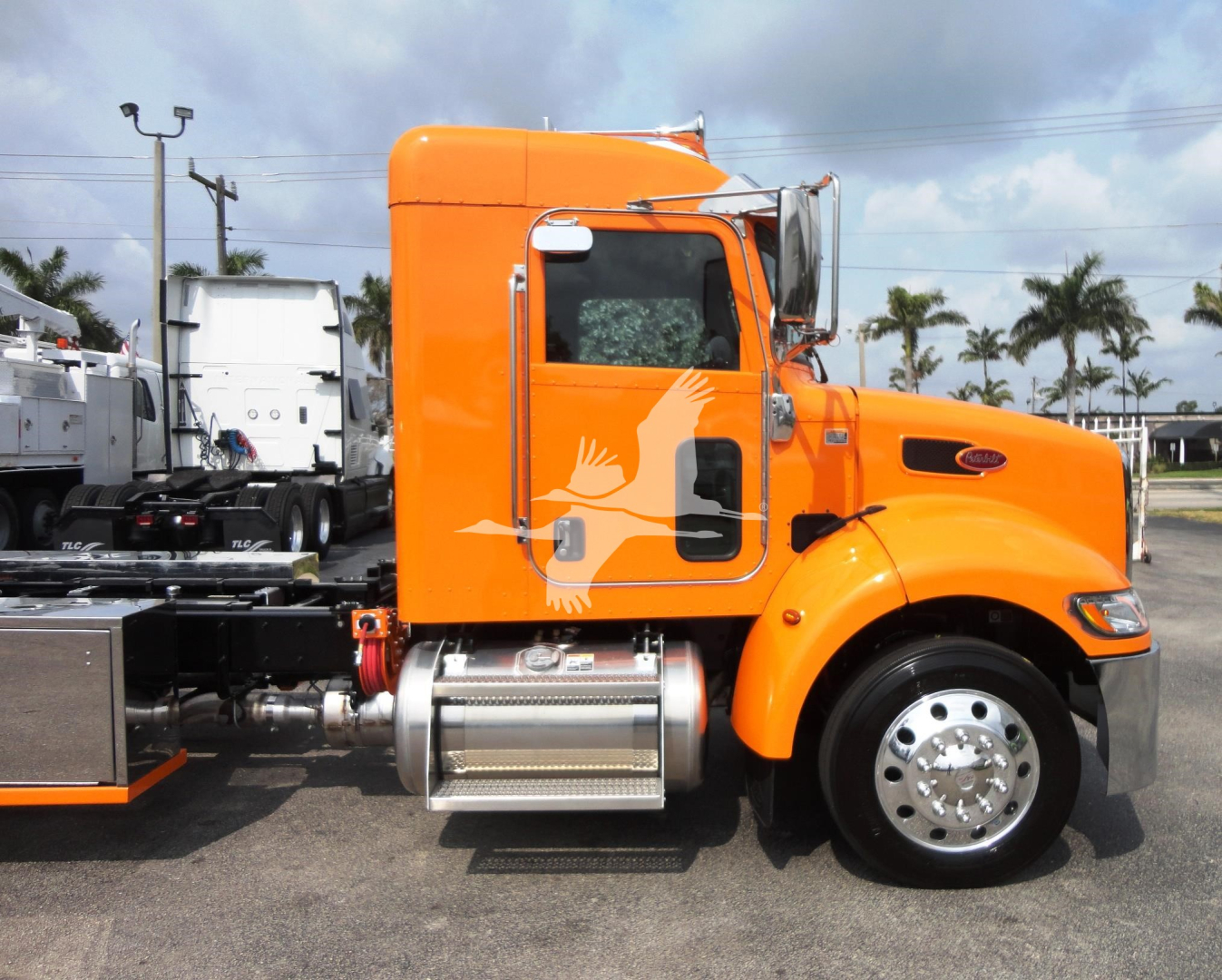 Peterbilt 337 rollback truck in orange side view showing cab and chrome fuel tank with steps.
