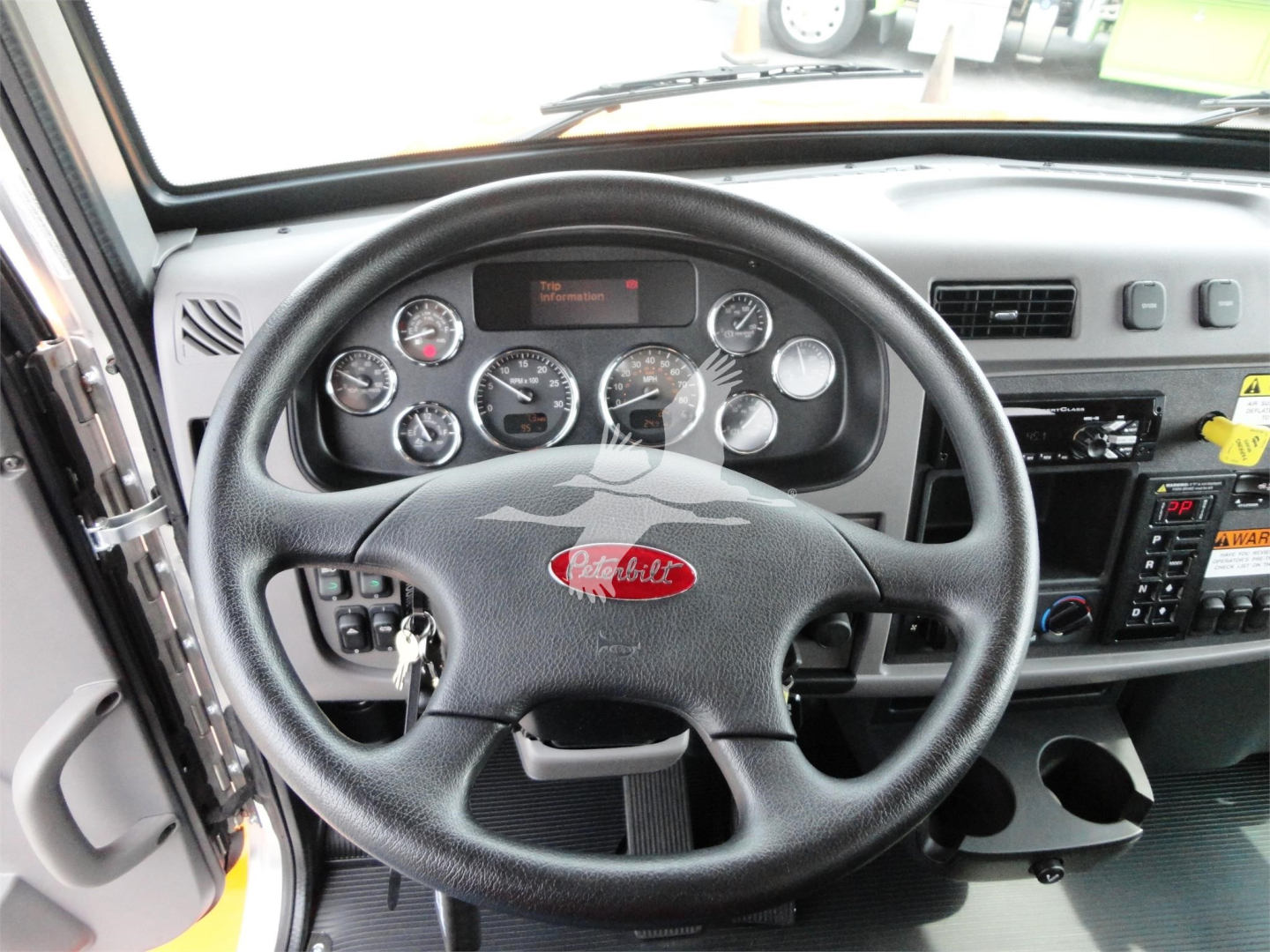 Peterbilt steering wheel and dashboard in cab showing gauges and controls.
