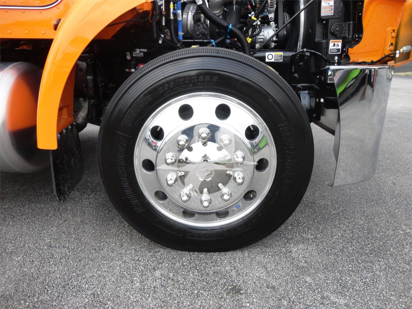 Peterbilt 337 wheel and front suspension view showing chrome hub, black tire, and orange fender.