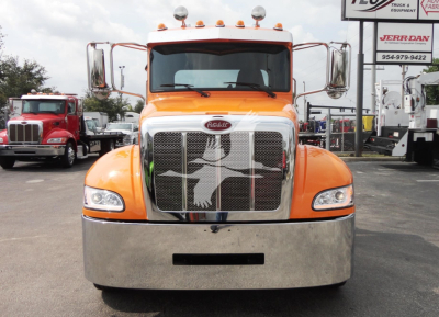 Peterbilt 337 front view with orange cab and chrome grille, large bumper, emblem on grille.