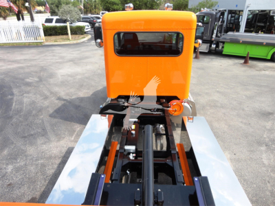 Orange Peterbilt 337 cab forward truck viewed from rear with rollback chassis and black drive shaft; chrome side rails and bright orange cab.
