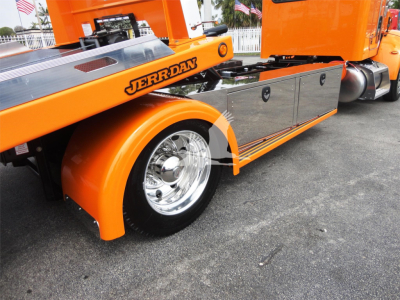 Peterbilt 337 rollback truck with bright orange paint and chrome wheels, side toolbox cabinets, and Jerr-Dan branding visible on the deck.