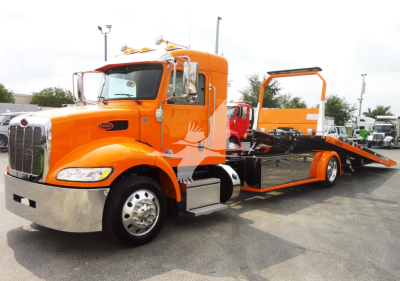 Orange Peterbilt 337 rollback tow truck shown in profile with flatbed and rear loading ramp.