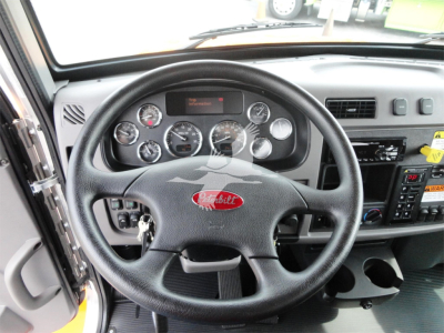 Peterbilt steering wheel and dashboard in cab showing gauges and controls.