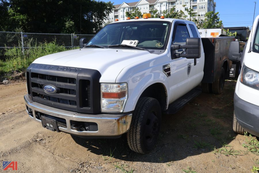 2008 Ford F-350 Super Duty utility truck in a lot, white cab, black grille, with side work utility bed and orange clearance lights on top.