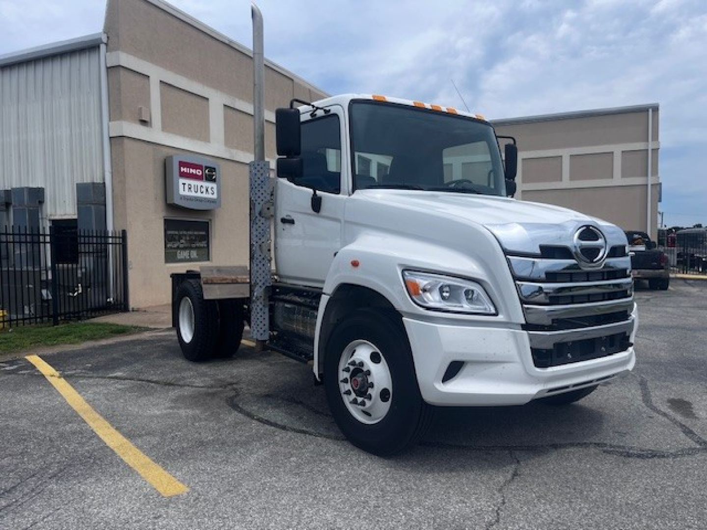 Hino XL7 cab and chassis truck in white parked outside dealership with stock number 69713 and VIN visible on listing.