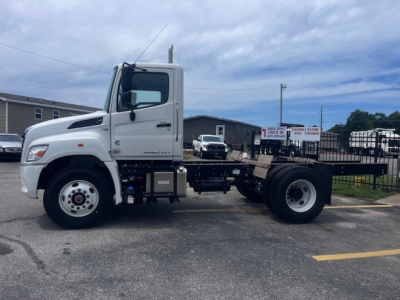 Truck chassis view of a 2026 Hino XL7 Cab and Chassis showing white cab, front wheel, and bare frame with rear wheels; VIN and stock number not visible in text on image.