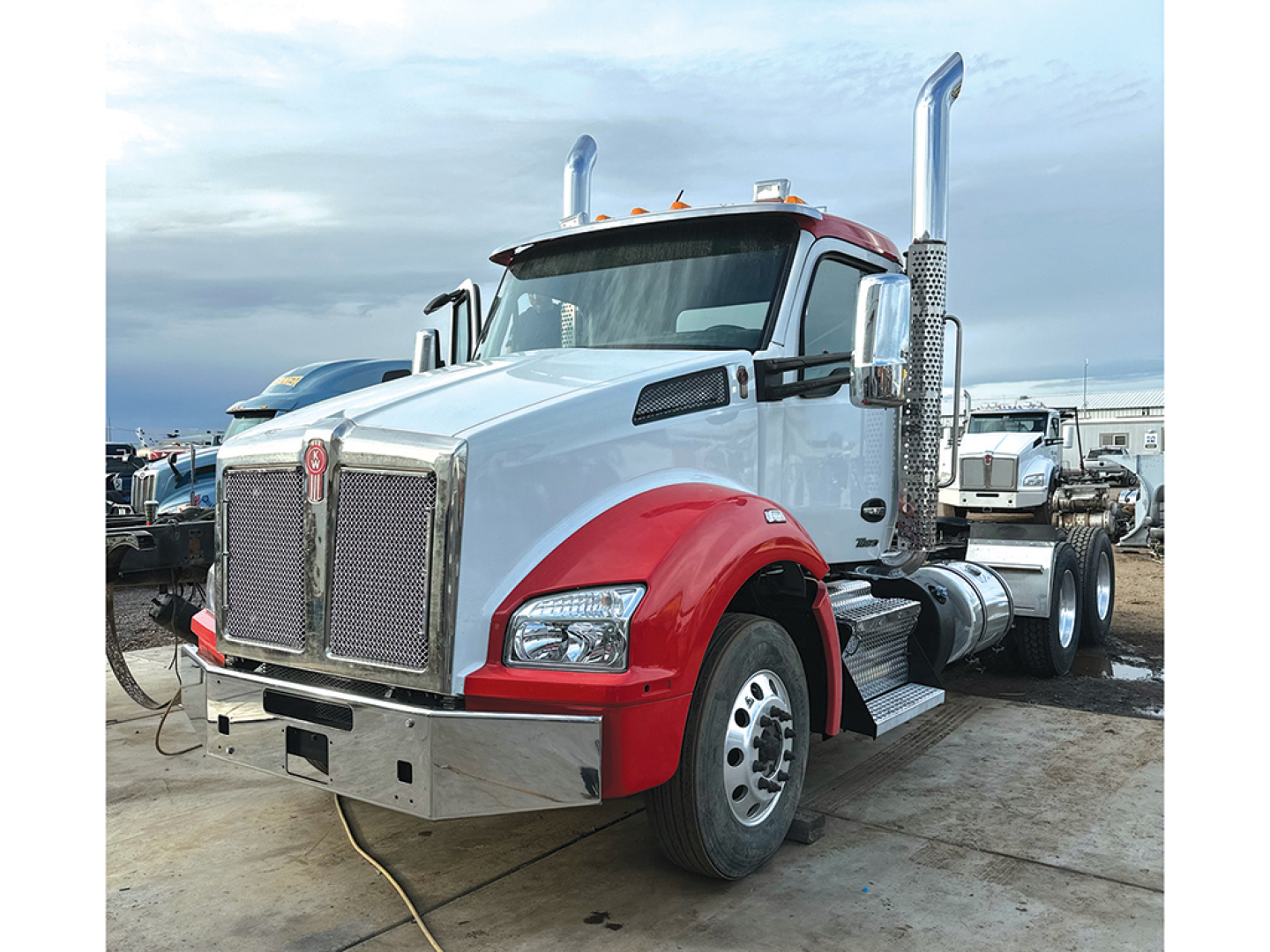 Kenworth T880 conventional daycab truck with chrome grille, red fenders, large exhaust stacks, cab mirrors, and front bumper.