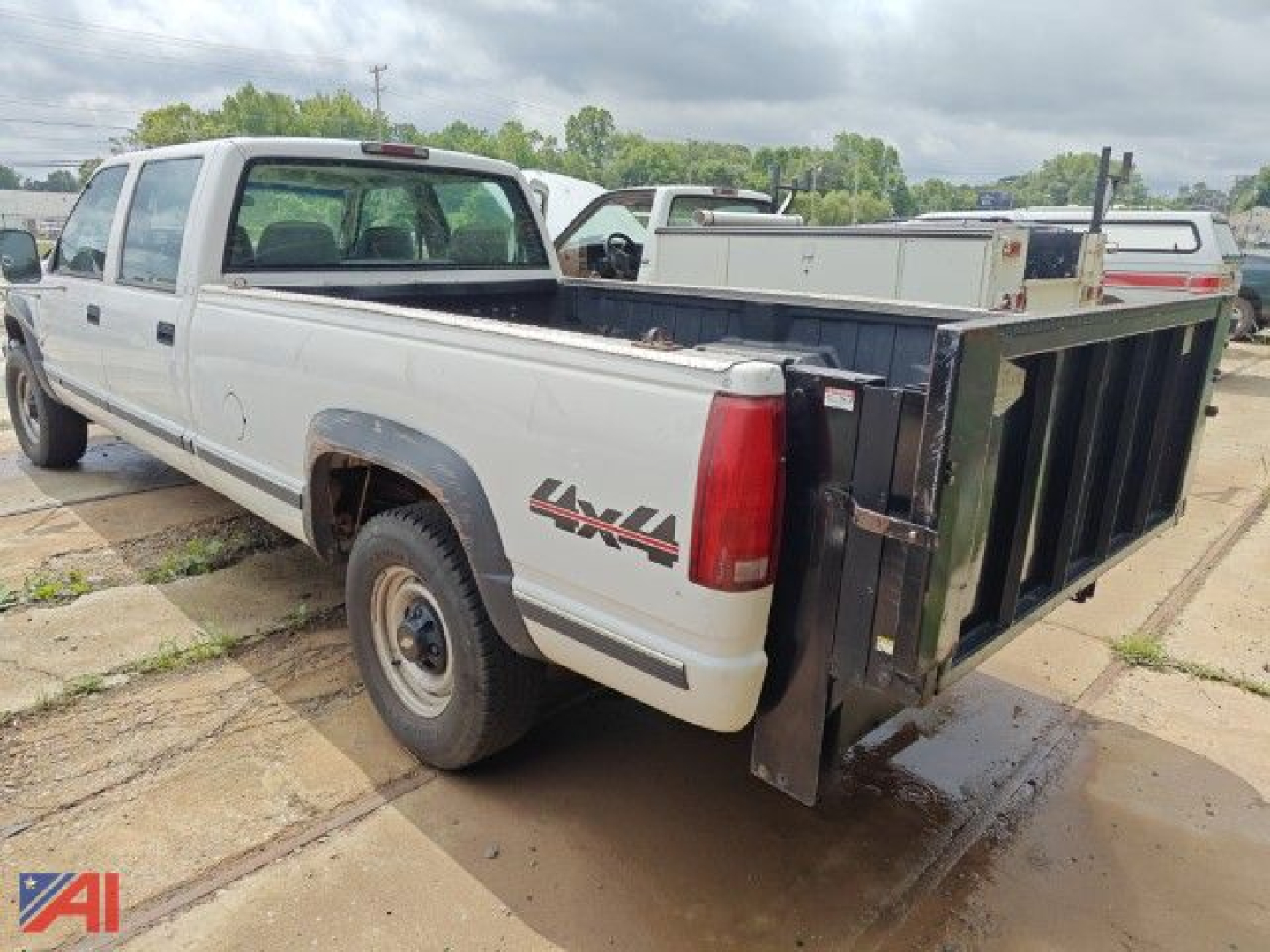 Chevrolet K3500 crew cab pickup truck with liftgate, in-service four-wheel drive, white with black dump bed at rear.