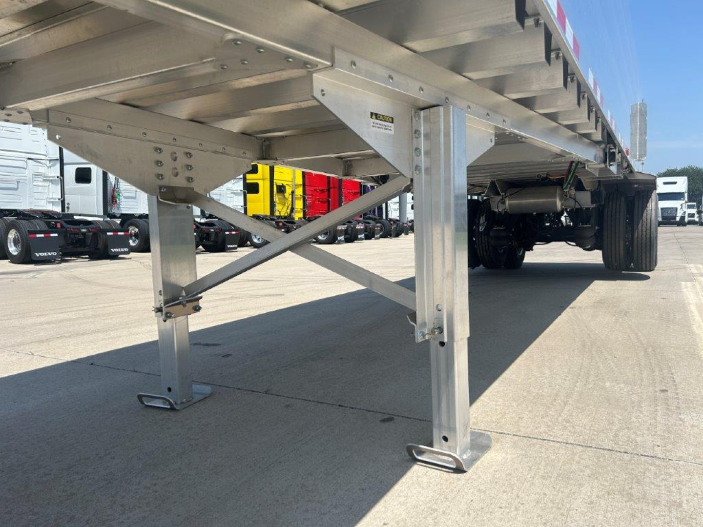 Aluminum flatbed trailer leg and frame showing support braces and wheel area.