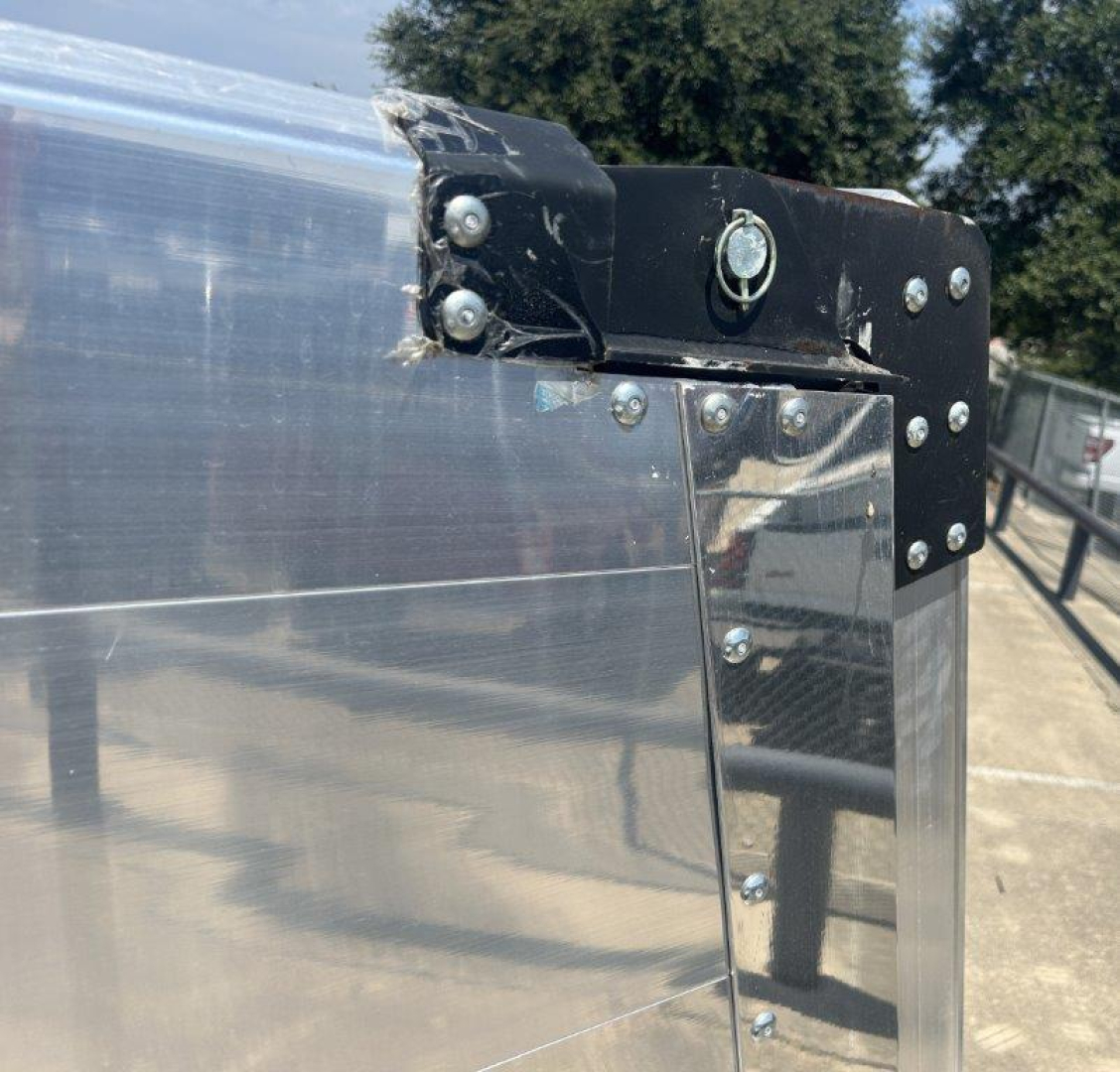 Trailer corner showing metal amp body with riveted joints and a black latch/hinge hardware.