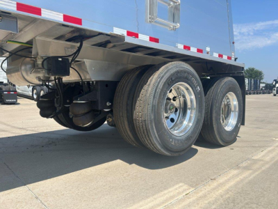 Triple-axle dump trailer tires and undercarriage showing dual rear wheels, metal framing, and underbelly components