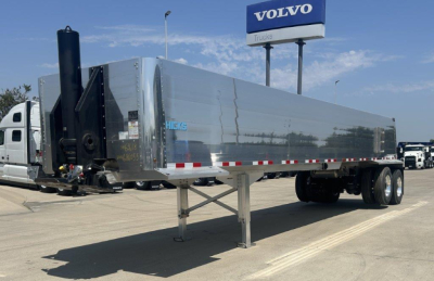 Dump trailer by Hicks showing silver sides, logo 'HICKS' near front, black front assembly with hydraulic hoist, dual rear axles, gooseneck hitch and landing legs.