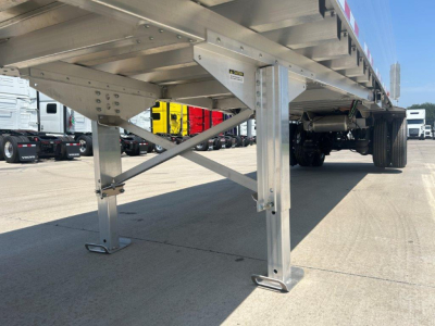 Aluminum flatbed trailer leg and frame showing support braces and wheel area.