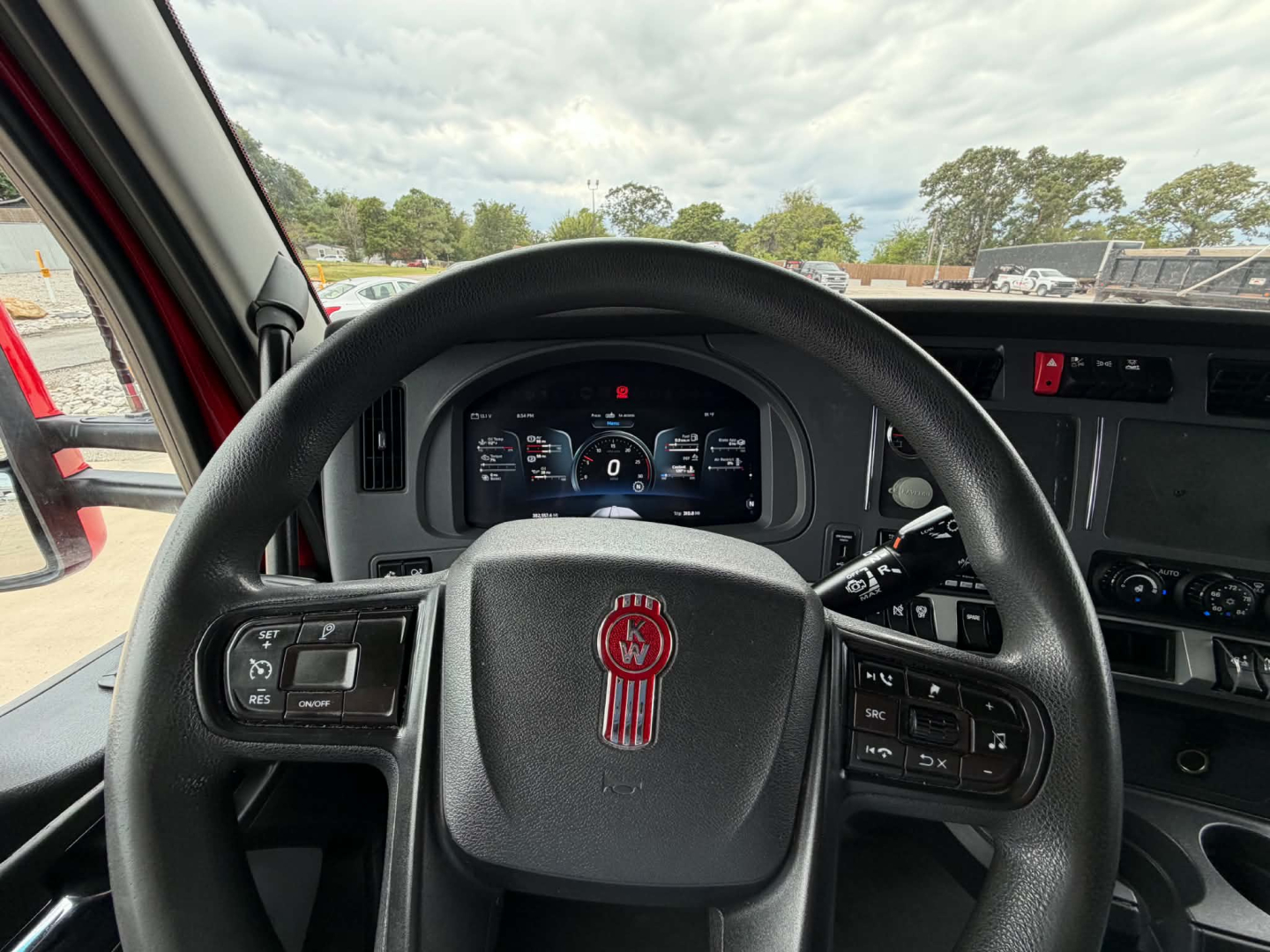 Kenworth T680 cockpit steering wheel and dash view showing steering wheel logo and digital gauges.