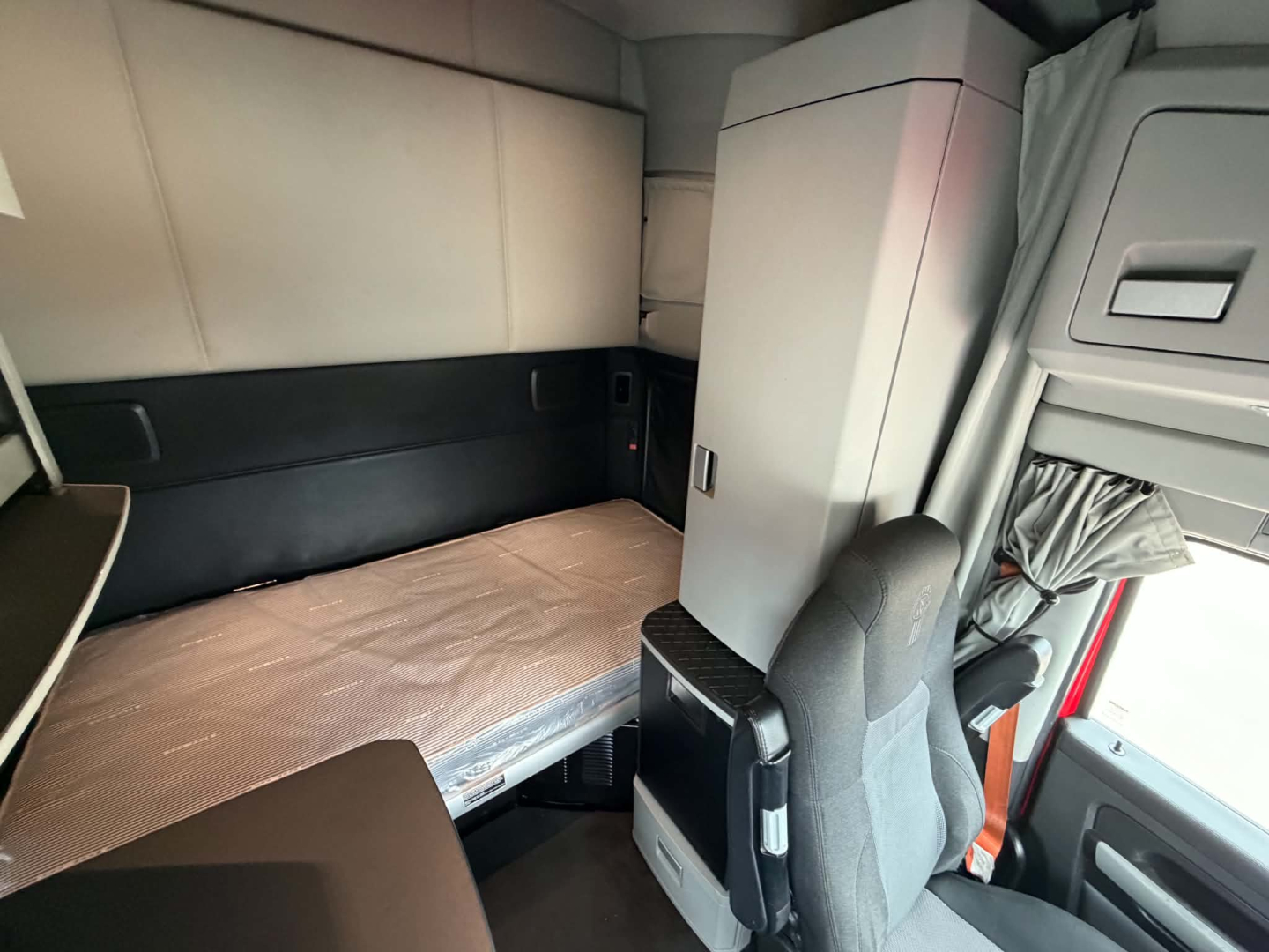 Kenworth T680 sleeper cab interior showing bunk bed area and driver's seat.