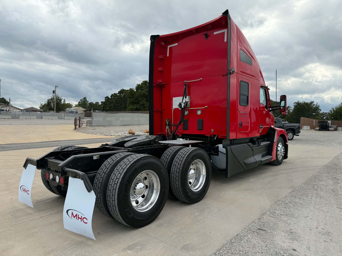 Kenworth T680 tractor with red cab, view of rear and dual rear axles, exhaust and fuel tanks visible.