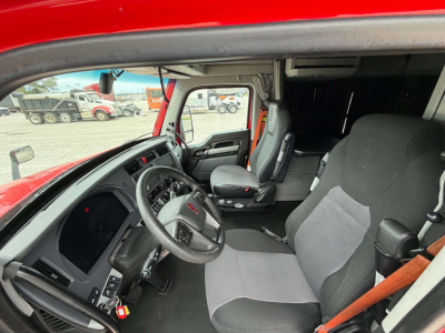 Kenworth T680 cab interior showing steering wheel, dashboard, driver seat, and passenger seat in a red truck.
