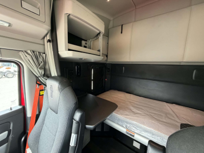 Kenworth T680 sleeper cab interior showing bunk bed and overhead storage.