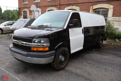 Chevrolet Express cargo van front-side view showing black and white police/utility van with dual-tone paint, amber turn signal, Chevrolet emblem on grille.