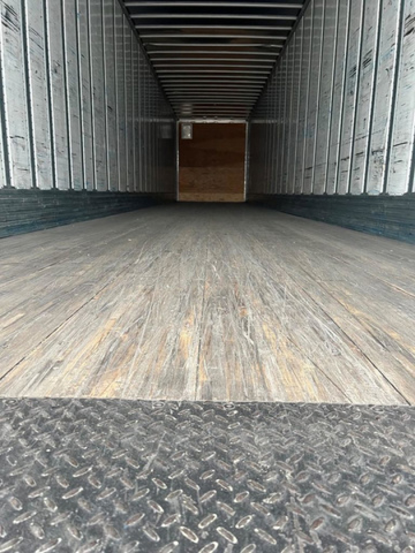 Trailer interior showing wooden floor and metal sidewalls with a rear cargo opening