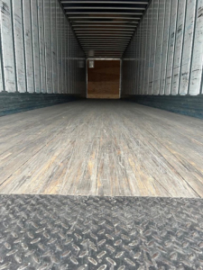 Trailer interior showing wooden floor and metal sidewalls with a rear cargo opening
