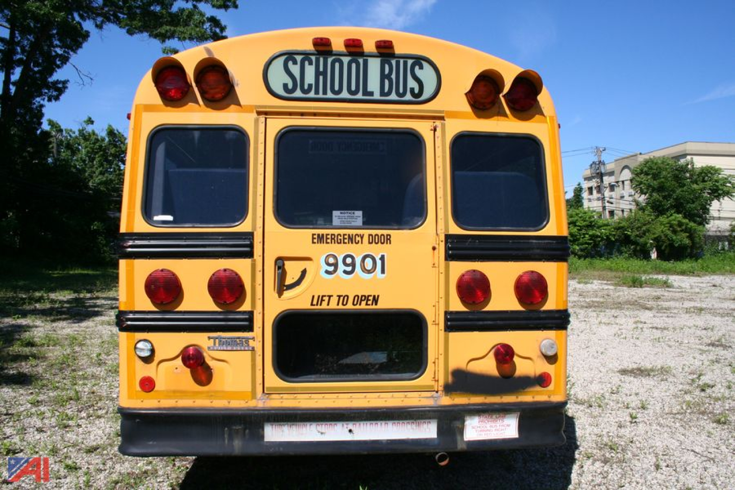 Rear view of a yellow school bus with 'SCHOOL BUS' sign, emergency door, and model number 9901 on the back.