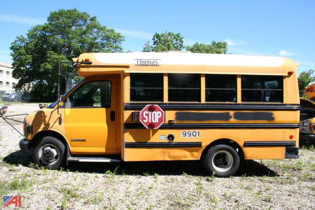 School bus side view showing Thomas logo atop the yellow body and stop sign extended.