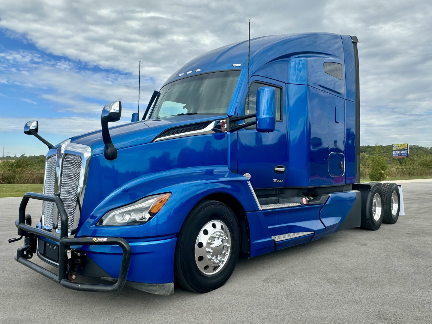 Kenworth T680 semi-truck in blue color shown from front-left angle with bull bar and sleeper cab.