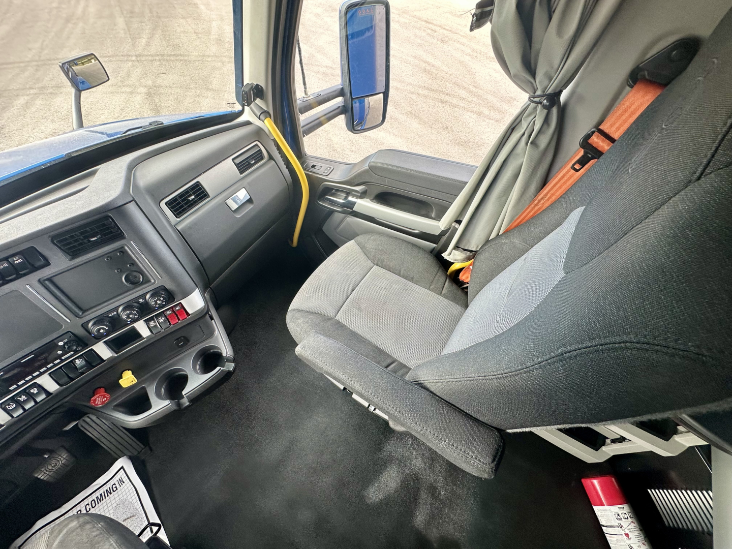 Kenworth T680 truck cabin interior showing driver's seat, dashboard controls, steering wheel, and side window with mirrors.