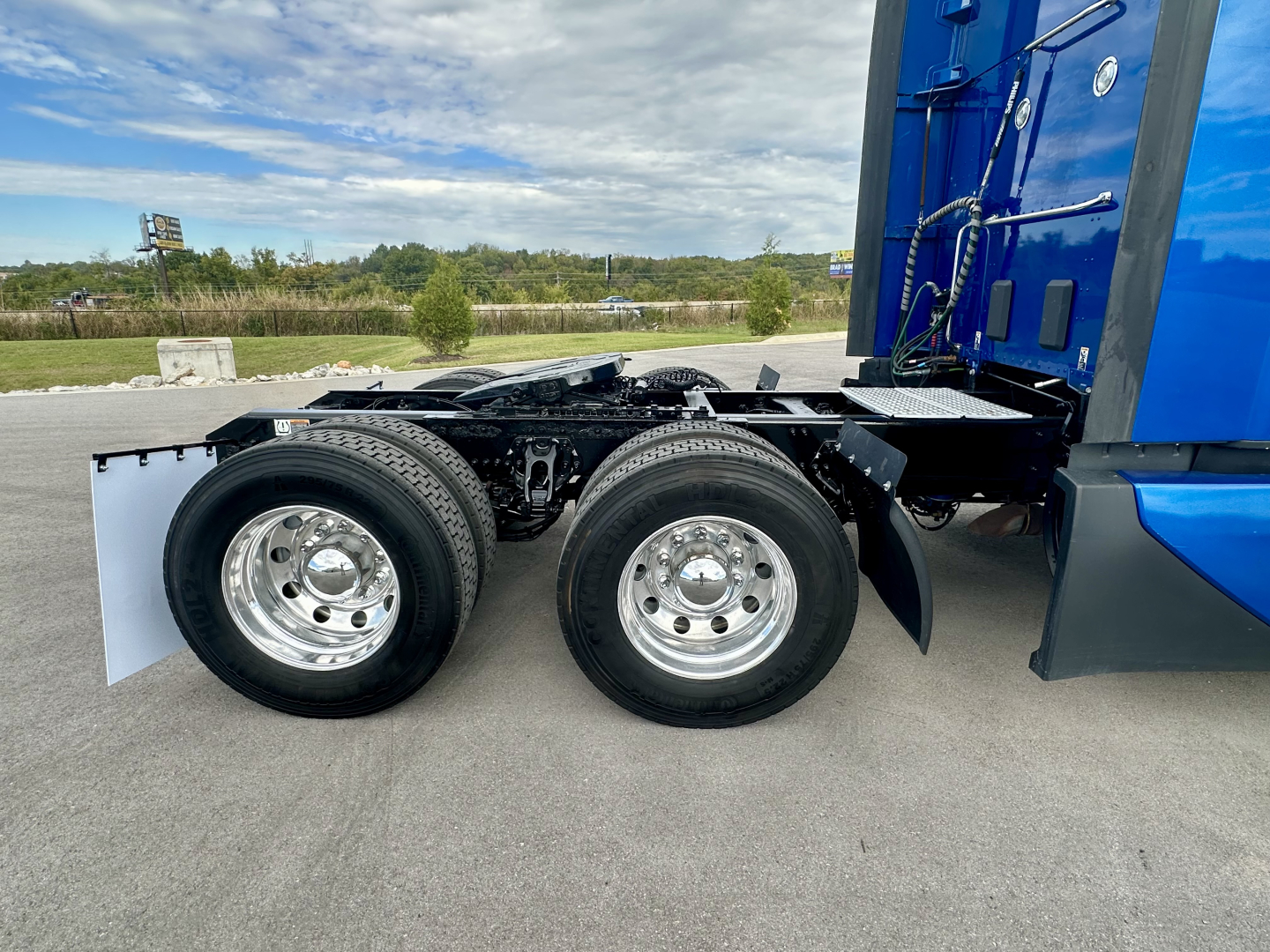 Kenworth T680 chassis showing rear dual axles and wheels with polished rims, side view of the cab, blue color, no background text visible.
