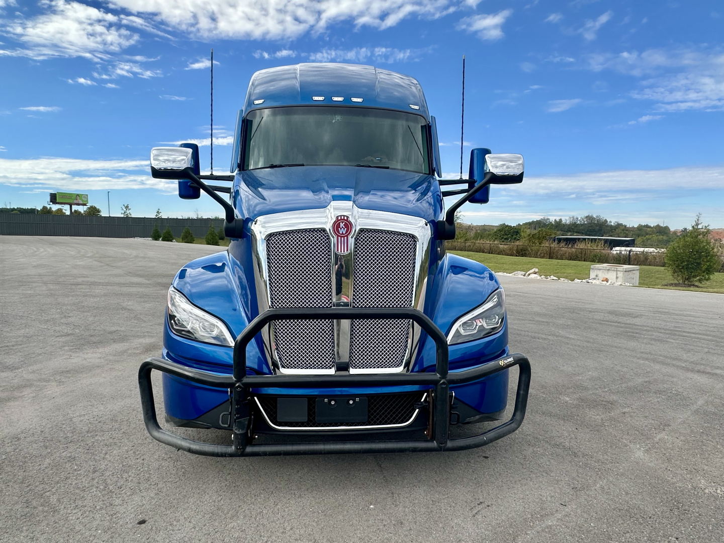 Kenworth T680 truck front view showing chrome grille, blue exterior, bumper guard, and headlights.