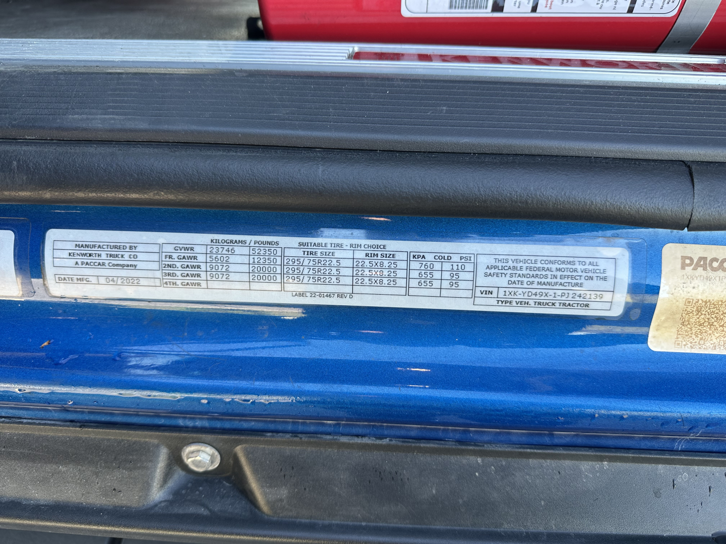 Label plate on blue Kenworth truck door jamb with various specifications and SKU numbers visible.