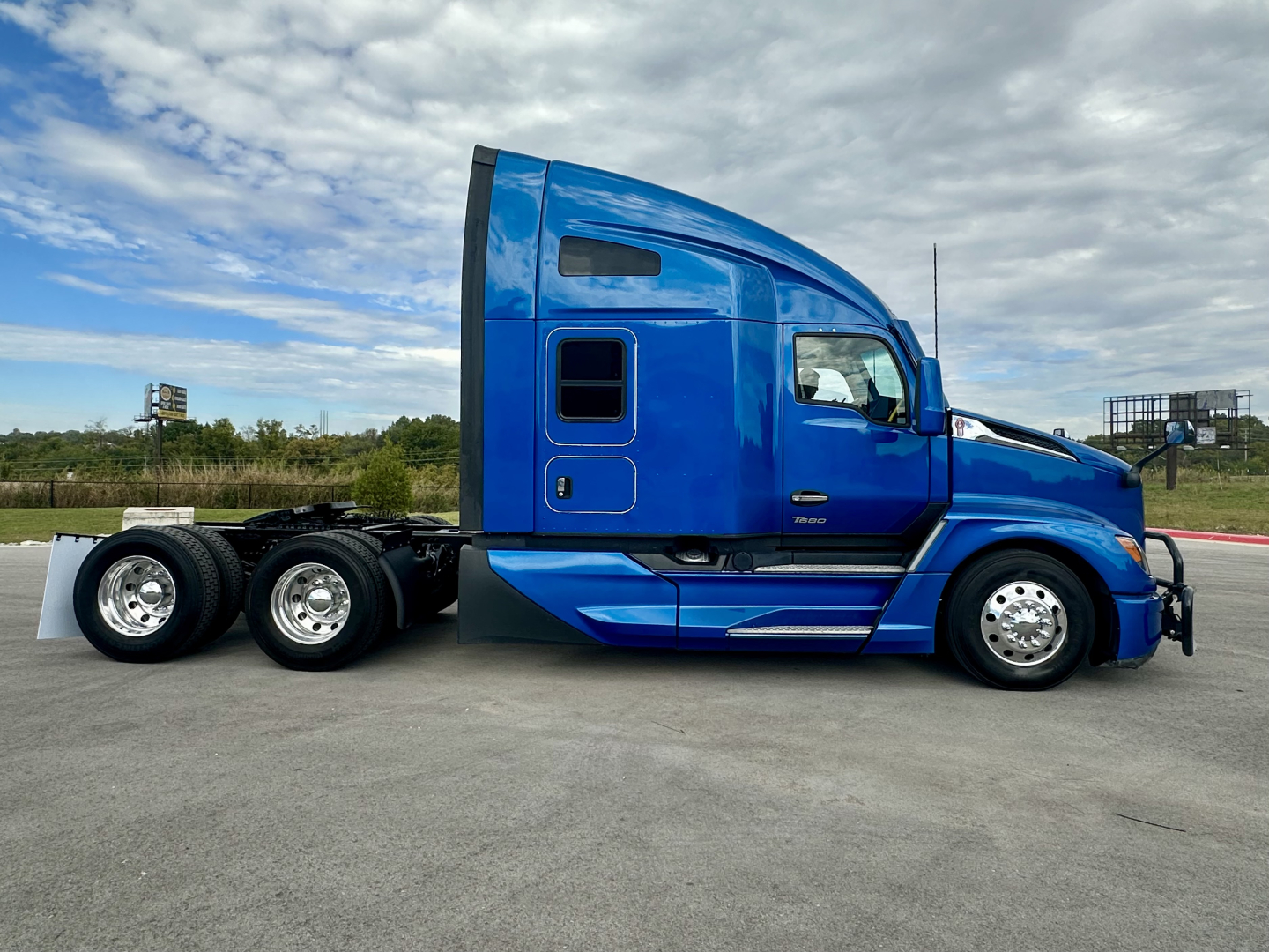 Kenworth T680 side view showing bright blue sleeper cab and tridem rear axle with six wheels.